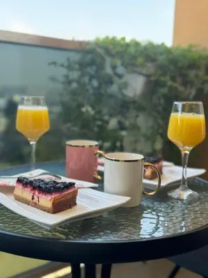 a table with a piece of cake and two glasses of orange juice at Apartman Krasula Doboj in Doboj