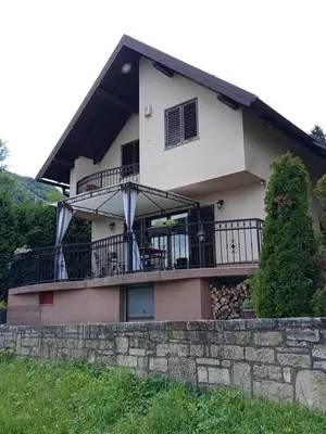 a house with a balcony and a stone wall at Holiday Home Dzeni in Zenica