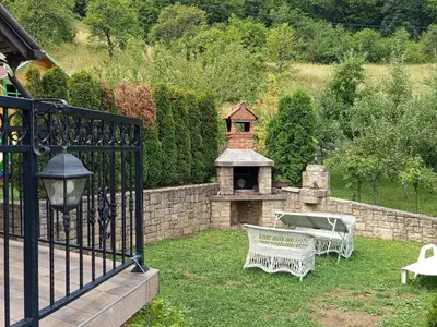 a garden with a grill and a table and a bench at Holiday Home Dzeni in Zenica