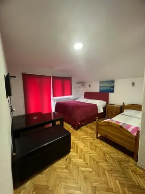 a bedroom with two beds and red curtains at Prenoćište SAMIR in Gradačac