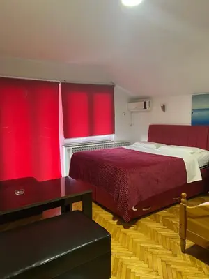 a bedroom with red curtains and a large bed at Prenoćište SAMIR in Gradačac