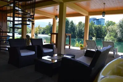 a patio with chairs and tables and a view of the water at Villa My Island in Bihać