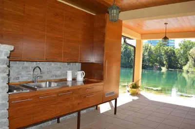 a kitchen with wooden cabinets and a view of a lake at Villa My Island in Bihać