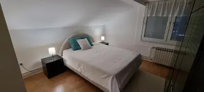 a bedroom with a bed with blue pillows and a window at Mott Residence in Tuzla
