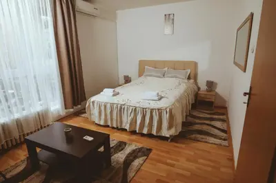 a bedroom with a bed and a table and a window at Apartman CENTAR 1 in Banja Luka