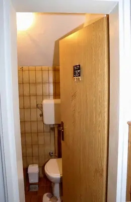 a bathroom with a toilet and a sign on the door at Merak Holiday Home in Visoko