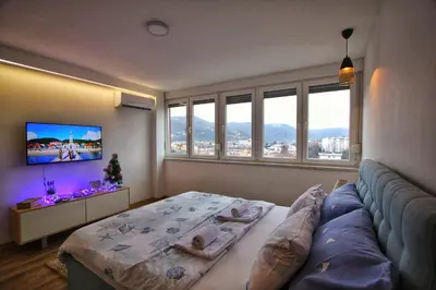 a bedroom with a bed and a couch and windows at Apartman Srdjan in Banja Luka