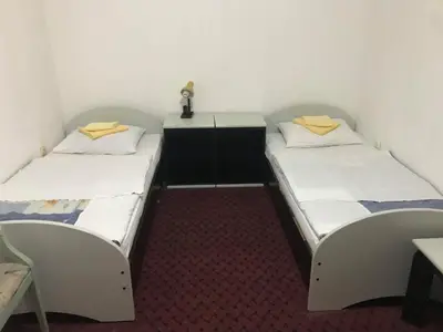 two beds in a small room with a table and chairs at Motel HEKO in Bugojno