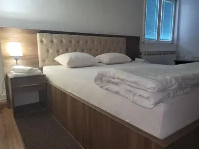a large bed with white sheets and pillows on it at Motel HEKO in Bugojno