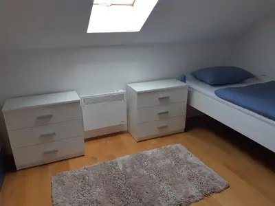 a bedroom with a bed and a dresser and a rug at Apartman Kupres Centar in Kupres