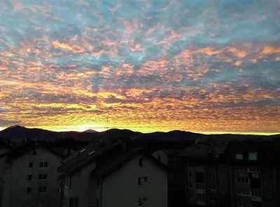 a sunset over a city with buildings and mountains at Apartman Kupres Centar in Kupres