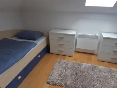 a bedroom with a bed and two dressers and a rug at Apartman Kupres Centar in Kupres