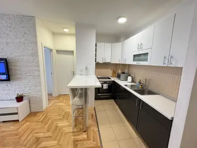 a kitchen with white cabinets and a wooden floor at Apartment 4th. Floor in Banja Luka