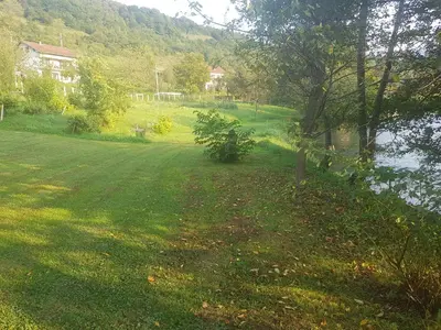 a grassy yard with a pond and a house at Vinac guest house in Jajce