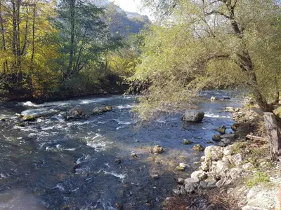 a river with rocks and trees on the side at Vinac guest house in Jajce