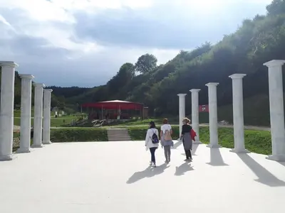 three women walking through a park with columns at Obiteljski Apartman Borovi in Visoko