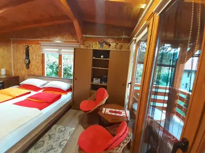 a bedroom with a bed and two red chairs at Obiteljski Apartman Borovi in Visoko