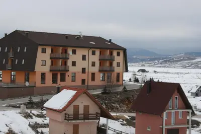 an apartment building with snow on the ground at Apartman Kupres Holiday in Kupres