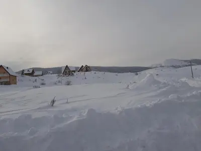 a field covered in snow with houses in the background at Apartman Kupres Holiday in Kupres