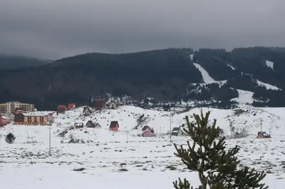 a snow covered field with houses and a mountain at Apartman Kupres Holiday in Kupres