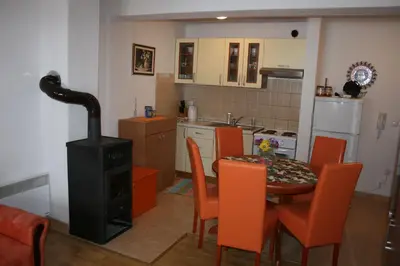 a kitchen with a stove and a table with orange chairs at Apartman Kupres Holiday in Kupres