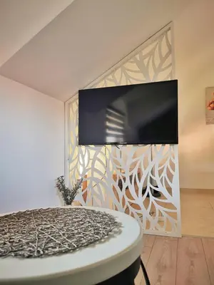 a bedroom with a tv on a wall and a table at Apartman Ananas Banja Luka centar bolnica besplatan parking in Banja Luka