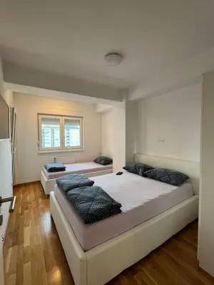 two beds in a room with wooden floors at Apartman Lukana in Banja Luka