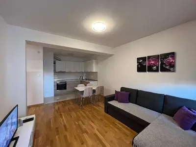 a living room with a black couch and a kitchen at Apartman Lukana in Banja Luka