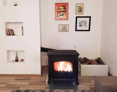 a fireplace in a living room with paintings on the wall at Guest house PiN in Laktaši