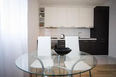 a kitchen with a glass table and white cabinets at Guest house PiN in Laktaši