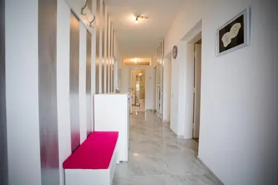 a corridor with a red bench in a white hallway at Guest house PiN in Laktaši