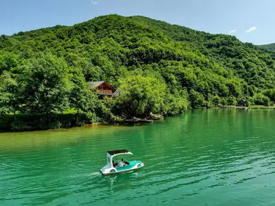 a small boat in the middle of a river at Forest Dream Lake House in Jajce