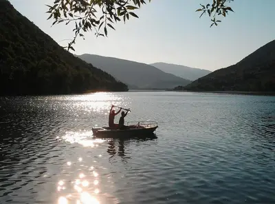 a small boat on a lake with mountains in the background at Forest Dream Lake House in Jajce