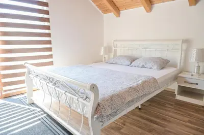 a bedroom with a white bed and a staircase at Forest Dream Lake House in Jajce