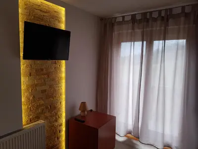 a room with a window with white curtains and a television at Vila Breza in Laktaši
