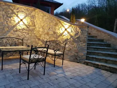 a stone wall with two chairs and a table on a patio at Vila Breza in Laktaši