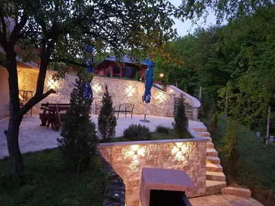 a backyard with a stone wall and stairs with lights at Vila Breza in Laktaši