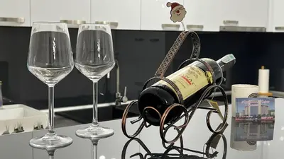 a bottle of wine is hanging between two wine glasses at apartman nejra in Tuzla