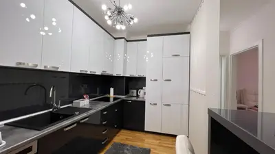 a kitchen with black and white cabinets and a sink at apartman nejra in Tuzla