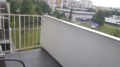 a balcony with a white wall and a view of a city at De Lux Apartment Maki in Banja Luka