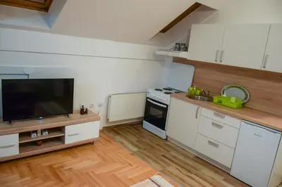 a kitchen with white cabinets and a flat screen tv at Apartman MAŠA in Banja Luka