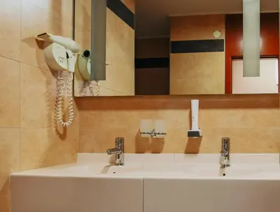 a bathroom with two sinks and a phone on the wall at Grand Hotel Tuzla in Tuzla