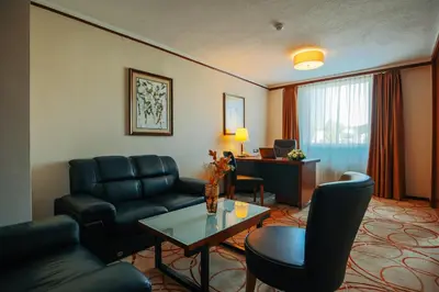 a living room with furniture and a desk in a hotel room at Grand Hotel Tuzla in Tuzla