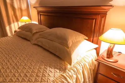 a bedroom with a bed with a wooden headboard and two lamps at Hotel San Terme Laktaši in Laktaši