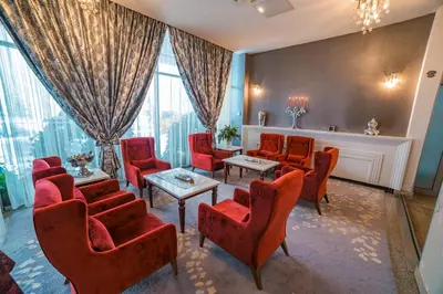 a waiting room with red chairs and tables at Hotel San Terme Laktaši in Laktaši