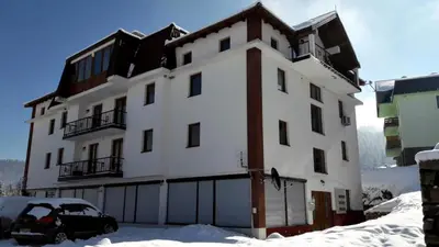 a large white building with a car parked in the snow at Apartments Vlašić in Vlasic