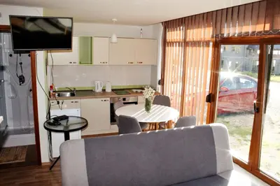 a kitchen and a living room with a table and a television at Apartments Vlašić in Vlasic