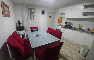 a kitchen with a white table and red chairs at Vila San in Banja Luka