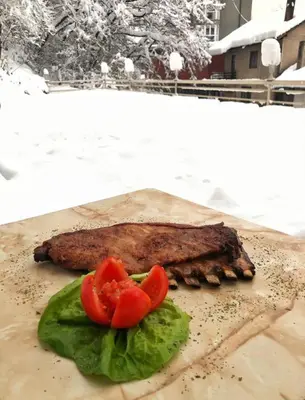 a piece of meat with tomatoes and lettuce on a table at Hotel Fontana in Zenica