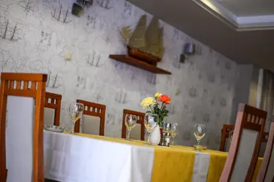 a table with wine glasses and a vase with flowers on it at Hotel Fontana in Zenica